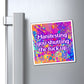 A square refrigerator magnet with a colorful paint splatter background and the text 'Manifesting you shutting the fuck up' in white with a purple outline, shown attached to a silver stainless steel refrigerator door next to the handle.