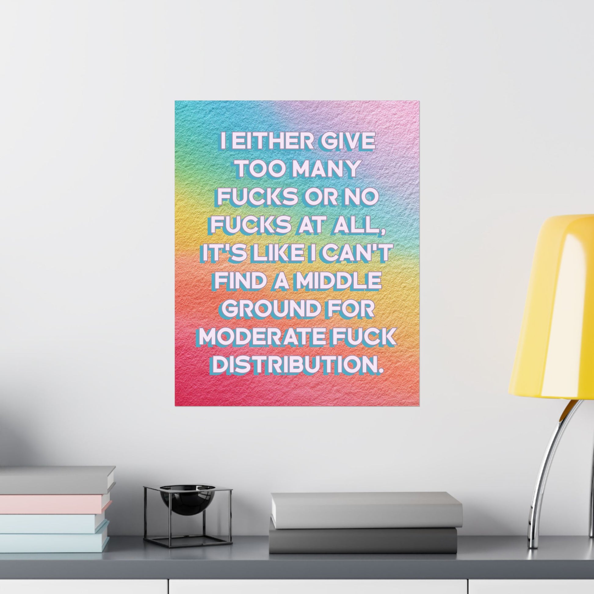 A square wall art print with a pastel rainbow gradient and bold white text reading, 'I EITHER GIVE TOO MANY FUCKS OR NO FUCKS AT ALL, IT'S LIKE I CAN'T FIND A MIDDLE GROUND FOR MODERATE FUCK DISTRIBUTION.' The print is displayed on a light gray wall above a shelf with books, a small decorative object, and a yellow lamp.