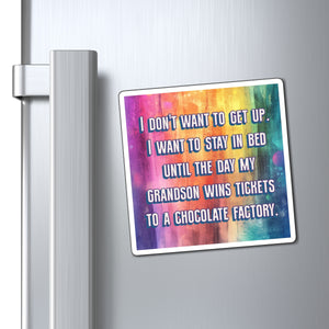 A square refrigerator magnet with a colorful watercolor background and humorous text, shown attached to a silver metal refrigerator door next to the handle.