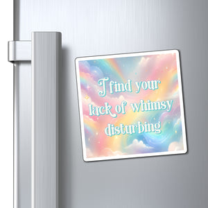 A square refrigerator magnet with a pastel rainbow background and the text 'I find your lack of whimsy disturbing' in light blue script, shown attached to a silver refrigerator door next to the handle.